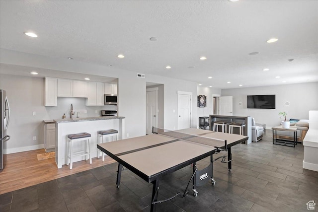6688 W Buck Dr, Herriman, UT 84096 - rec room with recessed lighting, baseboards, dark wood-type flooring, bar with sink, and a textured ceiling