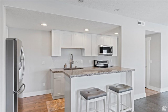 6688 W Buck Dr, Herriman, UT 84096 - kitchen featuring stainless steel appliances, a sink, baseboards, light wood finished floors, and a textured ceiling
