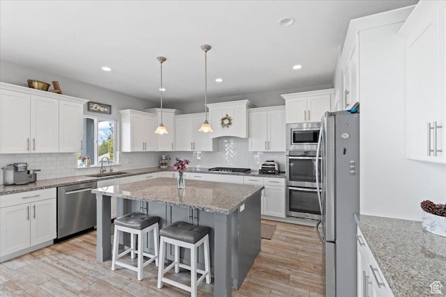 6688 W Buck Dr, Herriman, UT 84096 - kitchen with stainless steel appliances, a sink, white cabinets, decorative backsplash, and a breakfast bar