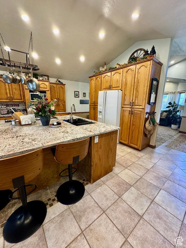1660 E 900 S Unit 19, Clearfield, UT 84015 - kitchen with white fridge with ice dispenser, a sink, light stone counters, vaulted ceiling, and brown cabinetry