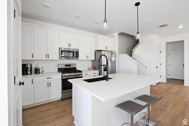 4945 W Willowbank Dr W, Highland, UT 84003 - kitchen with stainless steel appliances, an island with sink, tasteful backsplash, white cabinetry, and a breakfast bar