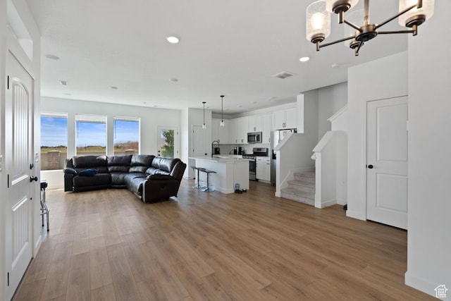 4945 W Willowbank Dr W, Highland, UT 84003 - living room featuring light wood-style flooring, recessed lighting, a chandelier, stairs, and baseboards