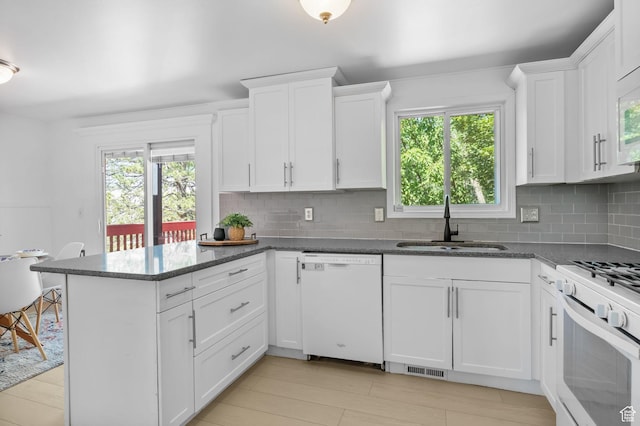 9224 S Benson Way, Sandy, UT 84070 - kitchen featuring white appliances, a sink, a peninsula, white cabinetry, and backsplash