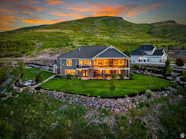 15113 S Cedar Meadow Cir, Herriman, UT 84096 - back of house at dusk with stairs, a yard, and a deck with mountain view