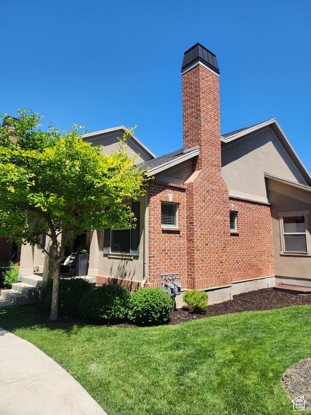 246 E Topspin Way, Lehi, UT 84043 - view of side of home with stucco siding, a yard, a chimney, and brick siding