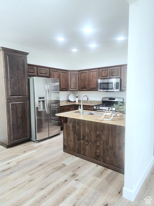 246 E Topspin Way, Lehi, UT 84043 - kitchen featuring appliances with stainless steel finishes, dark brown cabinetry, light wood-style flooring, light stone countertops, and a sink