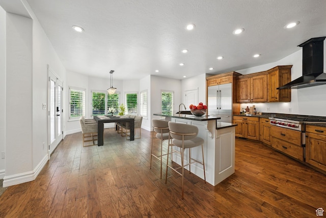 3444 N 180 E, Provo, UT 84604 - kitchen featuring wall chimney exhaust hood, stainless steel appliances, brown cabinets, dark countertops, and dark wood-style flooring
