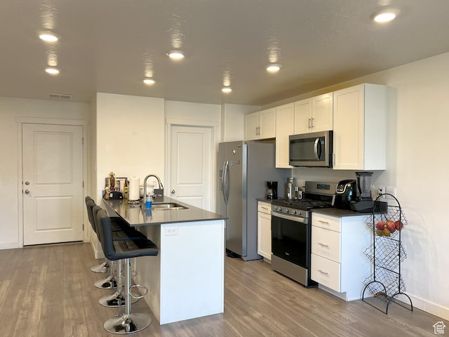 612 N Canvasback Dr, Lehi, UT 84043 - kitchen with stainless steel appliances, a sink, dark countertops, a breakfast bar area, and wood finished floors