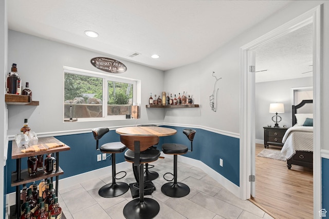 10927 S Lostwood Dr, Sandy, UT 84092 - tiled dining room featuring a bar, a textured ceiling, baseboards, and recessed lighting