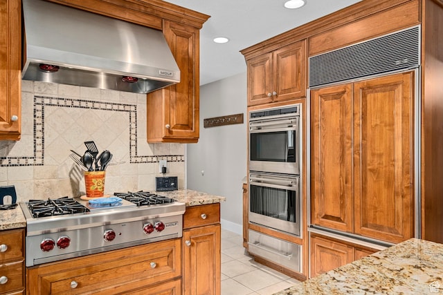 10927 S Lostwood Dr, Sandy, UT 84092 - kitchen featuring wall chimney exhaust hood, appliances with stainless steel finishes, backsplash, light tile patterned flooring, and brown cabinetry