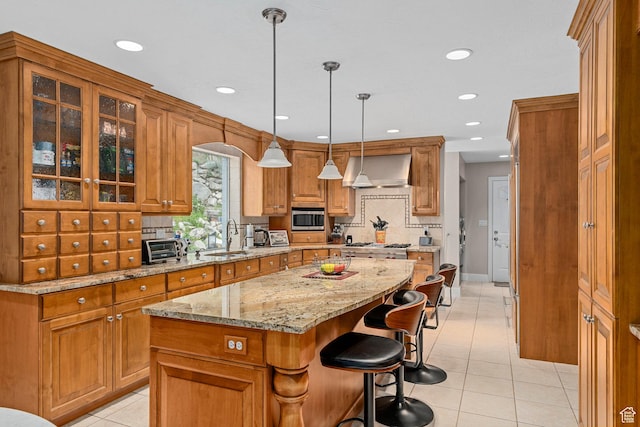 10927 S Lostwood Dr, Sandy, UT 84092 - kitchen with wall chimney exhaust hood, a sink, brown cabinets, a kitchen island, and light tile patterned floors