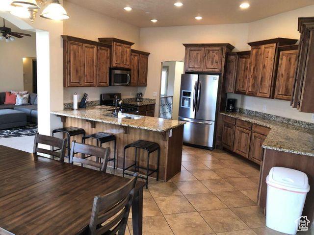 779 S 1850 W, Cedar City, UT 84720 - kitchen with appliances with stainless steel finishes, a sink, a peninsula, a ceiling fan, and light stone counters