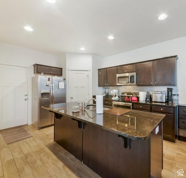 269 W Willow Dr, Saratoga Springs, UT 84045 - kitchen featuring appliances with stainless steel finishes, a sink, dark brown cabinets, a kitchen bar, and recessed lighting