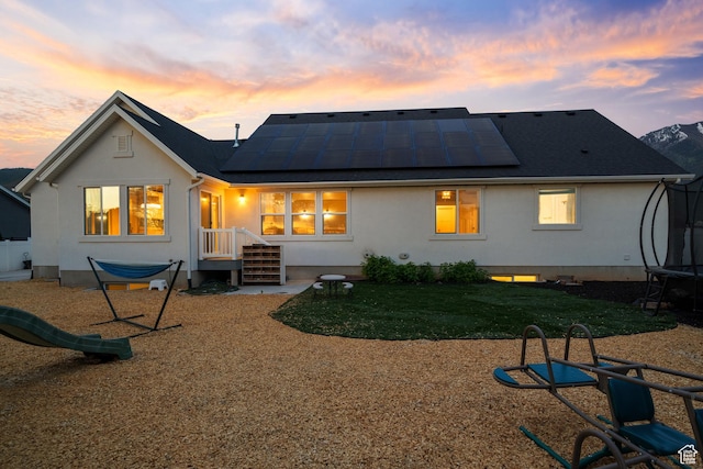 1047 N 700 W, Mapleton, UT 84664 - back of property with a trampoline, roof mounted solar panels, and stucco siding