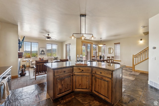 5430 N Cross Country Way, Park City, UT 84098 - kitchen with baseboards, a kitchen island, stone tile floors, a ceiling fan, and brown cabinets