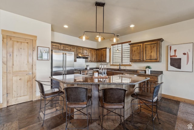 5430 N Cross Country Way, Park City, UT 84098 - kitchen featuring a sink, under cabinet range hood, baseboards, a center island, and a kitchen breakfast bar