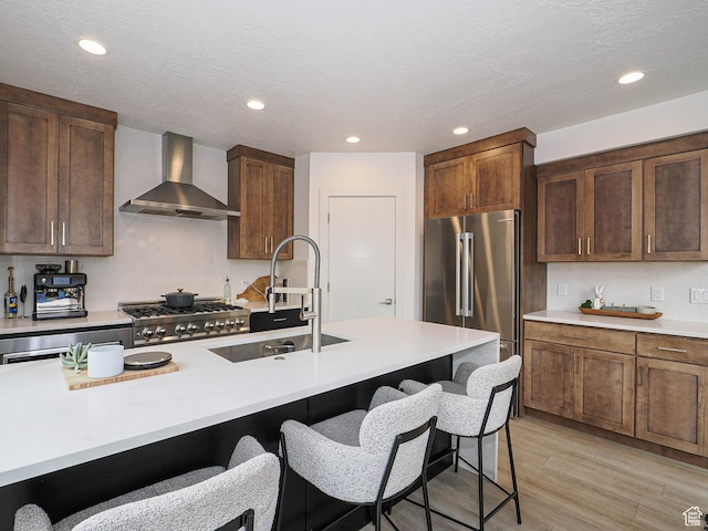 4535 S Bleecker Pl, Millcreek, UT 84117 - kitchen featuring wall chimney exhaust hood, high end fridge, a sink, range, and a breakfast bar area