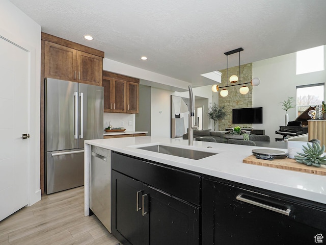 4535 S Bleecker Pl, Millcreek, UT 84117 - kitchen featuring appliances with stainless steel finishes, light countertops, open floor plan, decorative light fixtures, and a textured ceiling