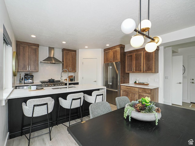 4535 S Bleecker Pl, Millcreek, UT 84117 - kitchen with high end refrigerator, wall chimney range hood, a sink, a kitchen breakfast bar, and light wood finished floors