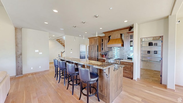 22677 E Snowbird Dr Unit 47, Spanish Fork, UT 84660 - kitchen featuring premium range hood, light wood-style flooring, a large island with sink, a breakfast bar, and recessed lighting