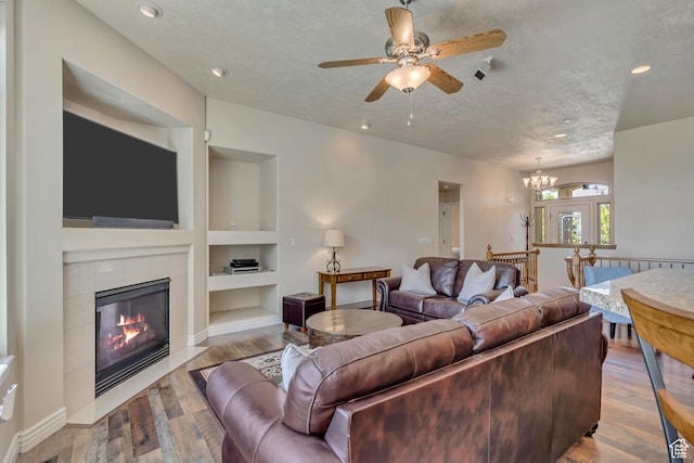 1804 E Longbranch Ct, Draper Ut Cnty, UT 84020 - living area featuring built in shelves, a tile fireplace, a ceiling fan, wood finished floors, and recessed lighting