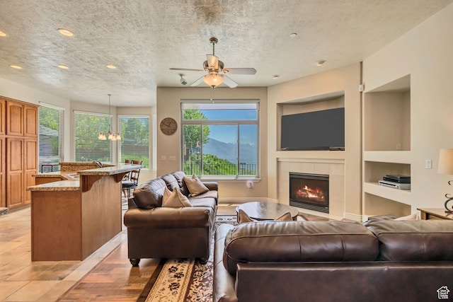 1804 E Longbranch Ct, Draper Ut Cnty, UT 84020 - living area featuring a textured ceiling, built in features, a tiled fireplace, ceiling fan, and recessed lighting