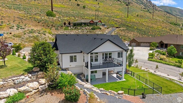 1243 Kotter Dr, Brigham City, UT 84302 - rear view of property featuring stucco siding, a patio area, a shingled roof, a mountain view, and a balcony
