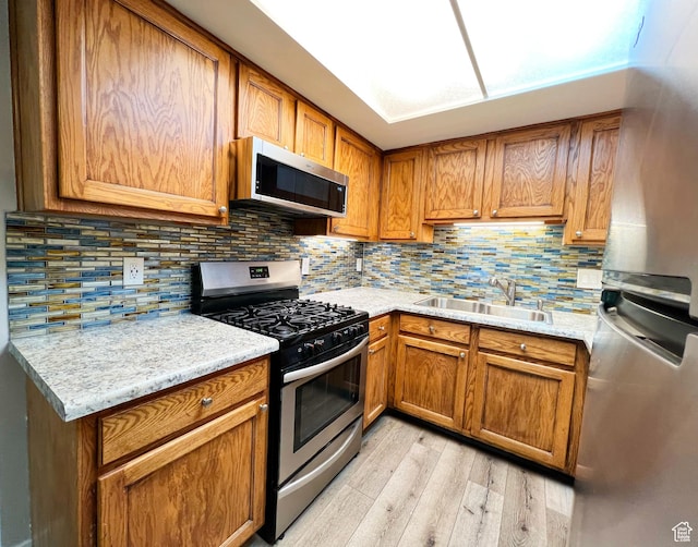 543 S 900 E Unit C3, Salt Lake City, UT 84102 - kitchen with stainless steel appliances, a sink, light wood finished floors, and brown cabinets