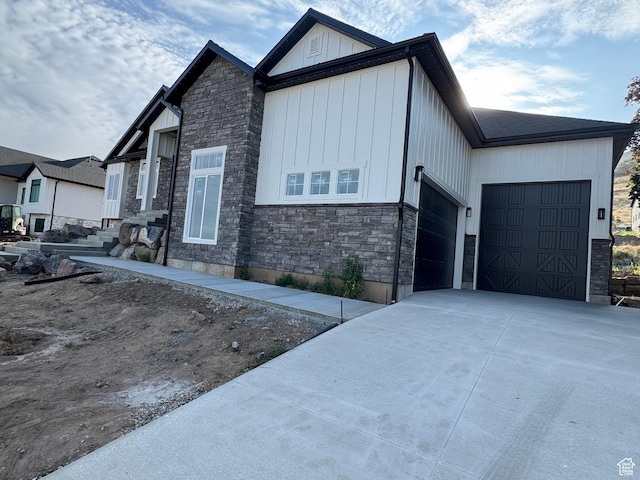2023 S 150 W, Perry, UT 84302 - view of side of property featuring stone siding, a garage, concrete driveway, and board and batten siding