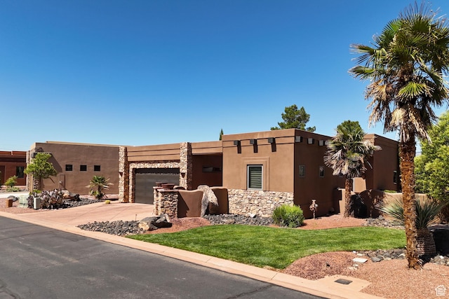 2090 N Tuweap Dr Unit 9, St George, UT 84770 - pueblo-style house with an attached garage, driveway, a front lawn, stucco siding, and stone siding