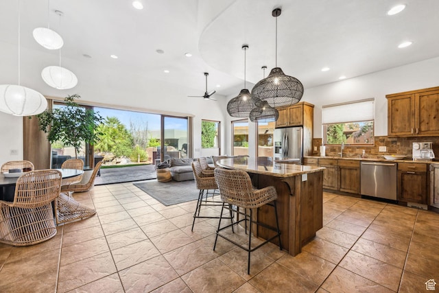 2090 N Tuweap Dr Unit 9, St George, UT 84770 - kitchen featuring appliances with stainless steel finishes, brown cabinetry, recessed lighting, decorative backsplash, and a center island