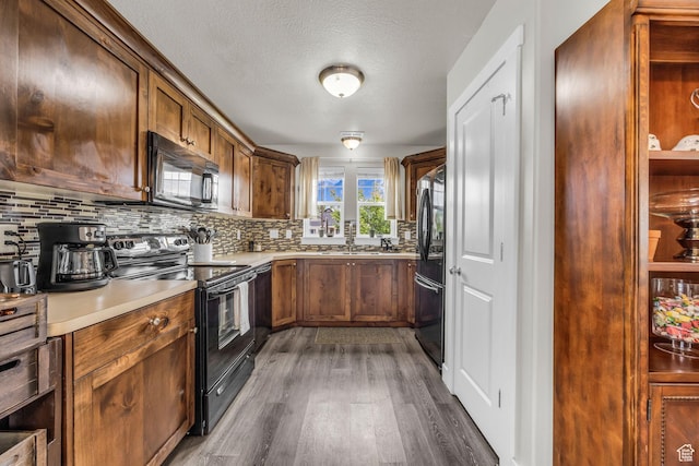 161 E 27th St S, Ogden, UT 84401 - kitchen with black appliances, dark wood-type flooring, backsplash, a sink, and light countertops