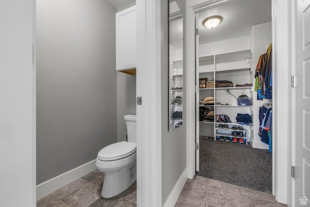3498 W Harvestwood Ln S, Riverton, UT 84065 - bathroom featuring toilet, baseboards, a walk in closet, and a textured ceiling