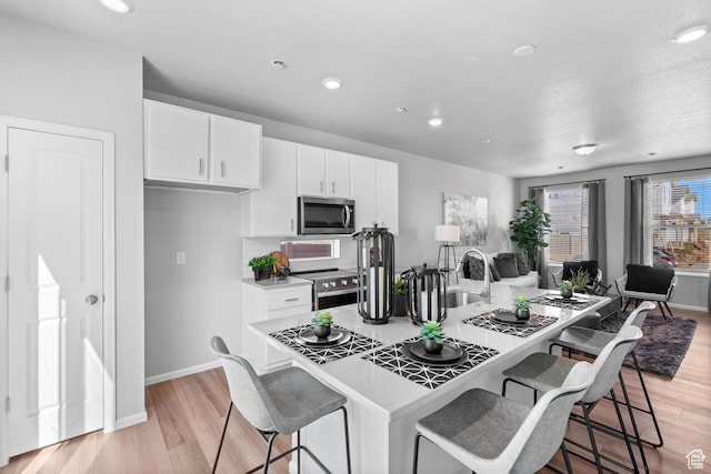 383 N Colonnade Rd Unit 1013, Saratoga Springs, UT 84045 - kitchen with stainless steel appliances, a breakfast bar area, white cabinetry, baseboards, and light countertops