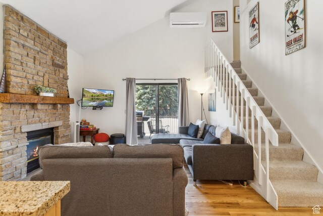 2025 Canyons Resort Dr Unit B7, Park City, UT 84098 - living area featuring high vaulted ceiling, a wall mounted AC, a fireplace, light wood-type flooring, and stairs
