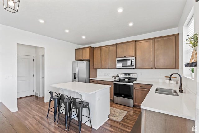 742 E Stonebriar Dr, Eagle Mountain, UT 84005 - kitchen with appliances with stainless steel finishes, a sink, a breakfast bar area, a kitchen island, and dark wood-style floors