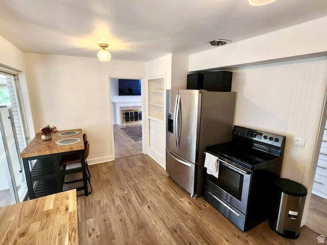 776 S Cherry Dr W, Orem, UT 84058 - kitchen with stainless steel appliances, a glass covered fireplace, wood finished floors, and baseboards