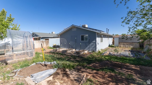 405 Bramblewood Dr, Cedar City, UT 84721 - rear view of house featuring a greenhouse, an outbuilding, a vegetable garden, and a chimney