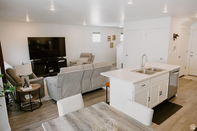 1859 N Blue Iris Ave Unit 1078, Tooele, UT 84074 - kitchen featuring a sink, dishwasher, a kitchen island with sink, white cabinetry, and light wood-style floors