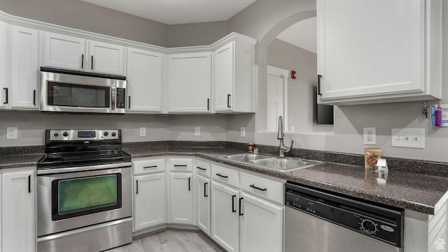 156 W Springview Dr Unit 505, Saratoga Springs, UT 84045 - kitchen featuring stainless steel appliances, a sink, white cabinetry, arched walkways, and light wood-style floors