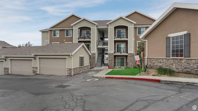 156 W Springview Dr Unit 505, Saratoga Springs, UT 84045 - view of property featuring stone siding, stucco siding, stairway, a garage, and asphalt driveway