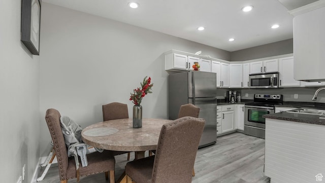 156 W Springview Dr Unit 505, Saratoga Springs, UT 84045 - kitchen with appliances with stainless steel finishes, a sink, dark countertops, light wood-style flooring, and white cabinets