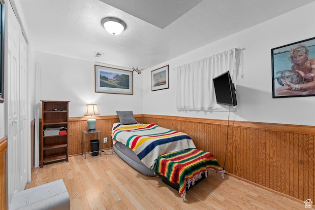 1616 E Waters Ln, Sandy, UT 84093 - bedroom with wainscoting, wood finished floors, wooden walls, and a textured ceiling