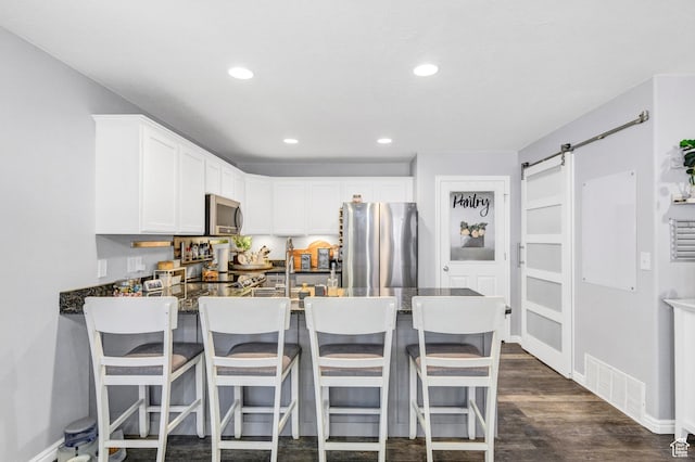 1038 N Plaza Dr, Richfield, UT 84701 - kitchen featuring stainless steel appliances, a peninsula, recessed lighting, white cabinets, and dark wood-style floors