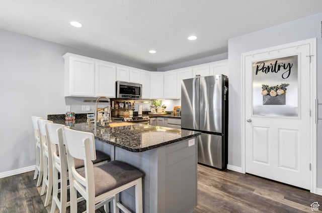 1038 N Plaza Dr, Richfield, UT 84701 - kitchen featuring stainless steel appliances, dark stone countertops, a peninsula, dark wood-style flooring, and white cabinets