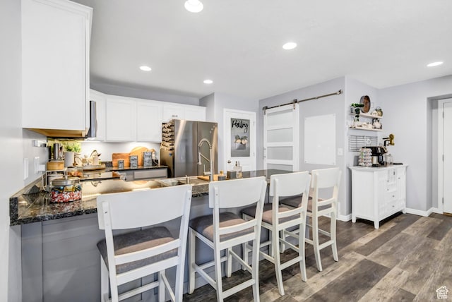 1038 N Plaza Dr, Richfield, UT 84701 - kitchen with a barn door, freestanding refrigerator, recessed lighting, white cabinets, and dark wood-type flooring
