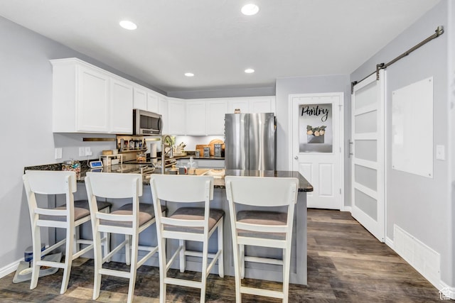 1038 N Plaza Dr, Richfield, UT 84701 - kitchen featuring stainless steel appliances, a peninsula, dark countertops, white cabinetry, and recessed lighting