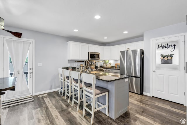 1038 N Plaza Dr, Richfield, UT 84701 - kitchen featuring appliances with stainless steel finishes, white cabinetry, dark wood-style flooring, dark stone countertops, and a peninsula