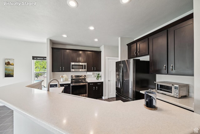 14499 S River Chase Rd, Herriman, UT 84096 - kitchen with stainless steel appliances, light countertops, dark brown cabinetry, and recessed lighting