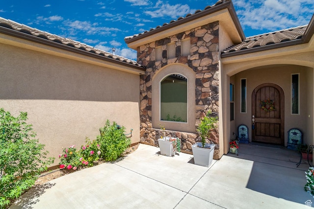 814 N High Ground Dr, Dammeron Valley, UT 84783 - property entrance featuring stone siding, a patio area, stucco siding, and a tile roof